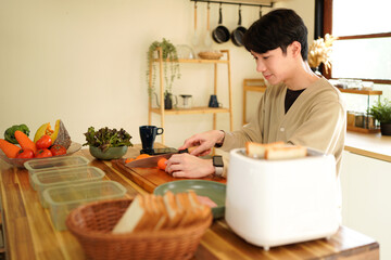 A man is cutting a carrot on a wooden cutting board.