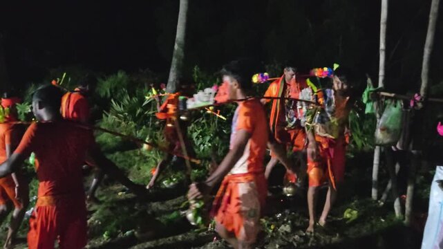 Authentic nighttime footage of Kanwariya devotees carrying beautifully decorated Kanwars during the sacred Kanwar Yatra in India. Captured from behind, the pilgrims walk together carrying holy water