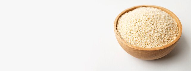 White sesame seeds in wooden bowl on white background. Organic sesame, cooking ingredient, Asian seasoning, source of calcium. Space for text