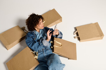 Fashionable young woman enjoying her shopping haul while using her phone