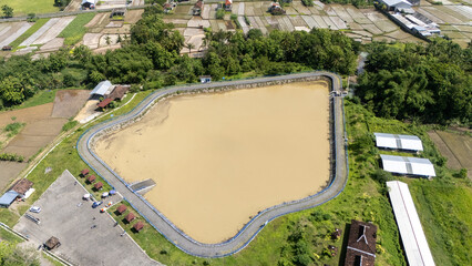 View of a big water reservoir lined with trees and fields, showcasing a tranquil rural setting,...