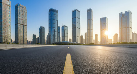 Modern city skyline with glass skyscrapers and wide empty road under clear blue sky at sunrise in urban financial district