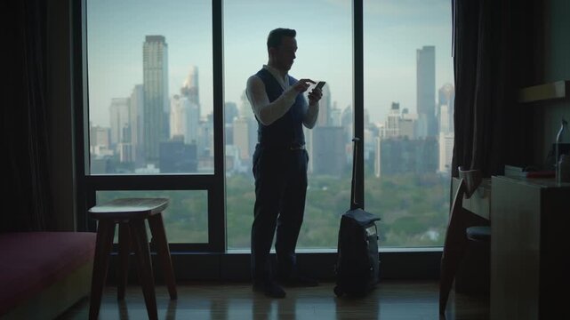 A businessman is situated in a hotel room that offers an impressive view of the cityscape