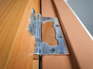 Metal hinge on a wooden interior door, repair, restoration. Close-up of the hinge holding the door.