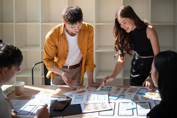 Diverse group of designers and developers discussing UX UI layouts and app prototypes in bright office space.