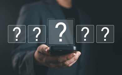 Businessman holding smartphone with floating question mark icons, representing decision making, uncertainty, problem solving, online help, innovation in digital business communication and technology.
