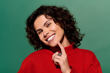 Fototapeta premium Fashionable young woman smiling confidently against a vibrant green background