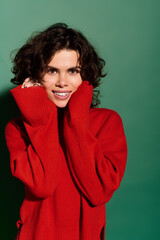 Obraz premium Young woman radiating joy in a stylish red sweater against a vibrant green backdrop
