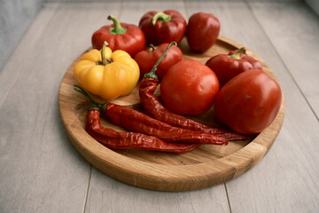 A beautiful, healthy selection of bell peppers, hot chili peppers, and tomatoes on a wooden surface. Highlights fresh, organic vegetables for a nutritious fall diet.