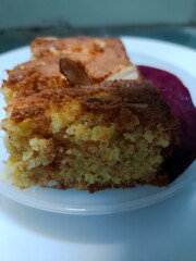 Close-up of a moist beetroot cake slice topped with almonds, served with fresh beetroot slices on a white plate. The golden crumb and vibrant color highlight healthy homemade baking and natural sweetn