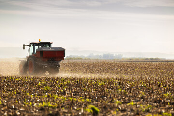 Tractor spreading artificial fertilizers in field