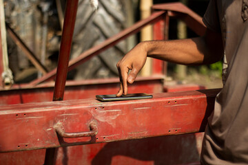 A persons hand taps on a smartphone placed on a red metal beam