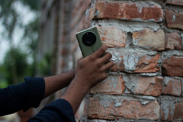 Person holding a smartphone against a brick wall