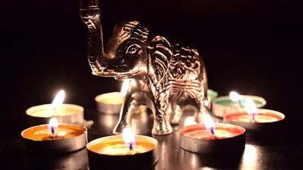 Small toy elephant and diyas, decorative lamps are lit during diwali, deepabali festival. It symbolizes the triumph of good over evil, light over darkness. Dipawali lights with dark background, India.