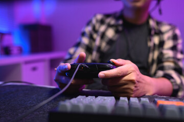 Closeup man playing video game at night with headset and neon RGB lighting