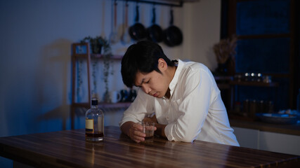 Depressed man sitting alone with glass of alcohol at night, symbol of loneliness and stress
