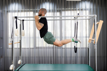 Cadillac and reformer, caucasian man doing Pilates exercises to strengthen body and stretch....