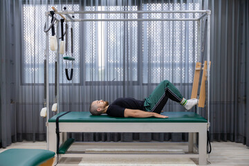 Cadillac and reformer, caucasian man doing Pilates exercises to strengthen body and stretch....