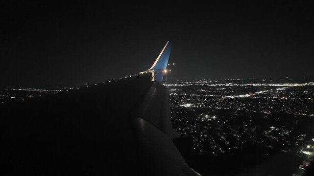 Airplane Landing at Night Over Detroit Airport With City Lights