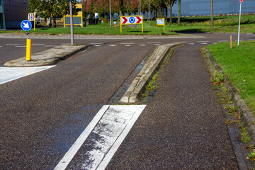 Road intersection featuring directional signs, painted lane markings, and a textured asphalt surface, illustrating urban navigation and traffic management concepts
