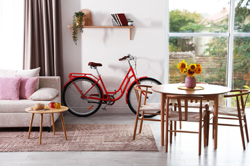Wooden dining table with chairs, sofa and bicycle in room