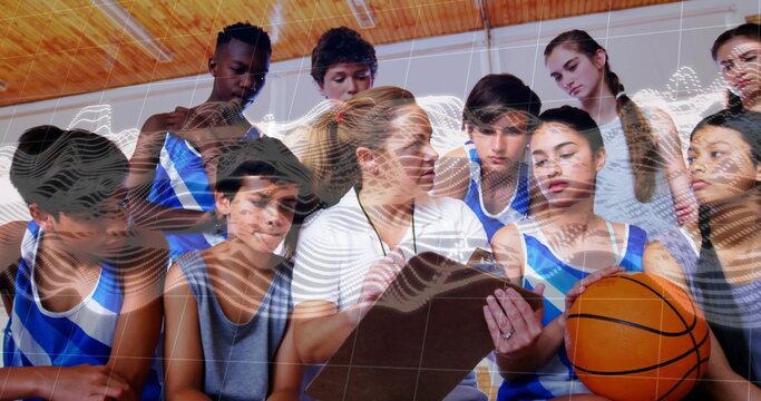 Female coach in white polo and whistle briefing players in gymnasium, with clipboard and basketball