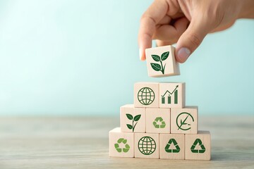 Hand stacking wooden blocks with environmental symbols to build a pyramid