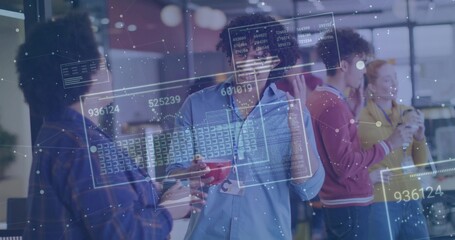 Holding red coffee cup, tech worker wearing lanyard discussing data panels in office lounge