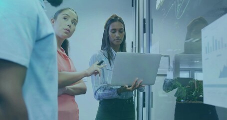 Discussing office team wearing business attire reviewing data sketches on glass wall, with laptop