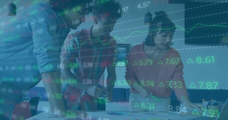 Three professionals leaning on conference table studying charts with green marker and market graphs