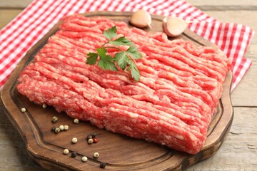 Raw minced meat with parsley and spices on wooden table, closeup