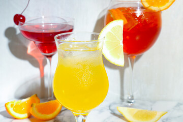Glasses of tasty cocktails with garnish on white marble table, closeup