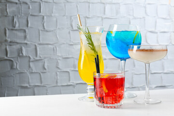 Glasses of tasty cocktails on white table, space for text