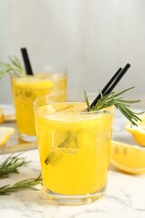 Glasses of tasty cocktails with lemon and rosemary on white marble table, closeup