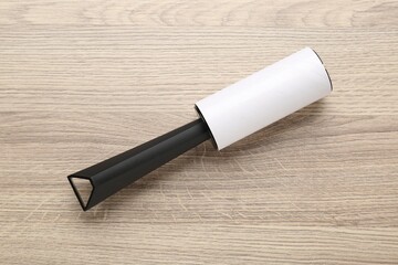 Sticky lint roller on wooden table, top view