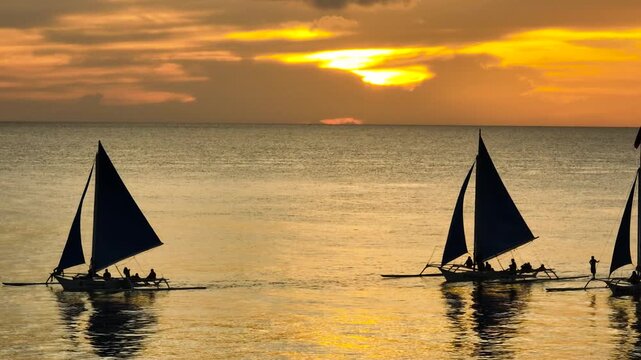 Cloudy Sunset over the paraw sailing boats running on sea water. Boracay, Philippines.