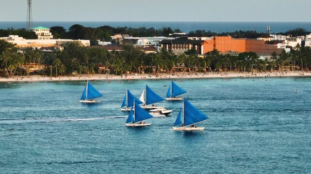 Sunset paraw sailing boats over the blue sea and powdery white sand beach in Boracay Island. Philippines.