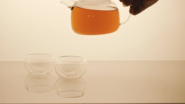 Teapot with black tea pouring in cap. 4K Video, slow motion