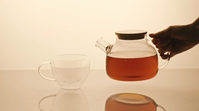 Teapot with black tea pouring in cap. 4K Video, slow motion