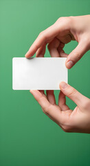 Close-up shot of two hands holding a blank white business card against a green background.