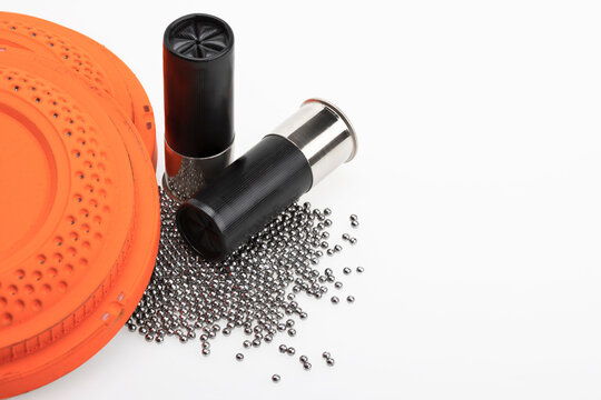Clay flying target and Shotgun shell ammunition with lead pellets on white background , gun and shooting game