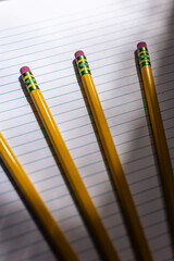 close-up of a pencils against lined notebook paper in moody lighting with copy space available