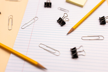 horizontal flat lay of office supplies: paper clips, pencils, manila folders, lined paper, and binder clips