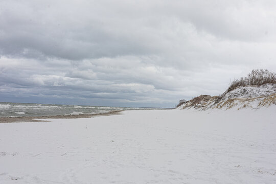Snowy Beach with Dunes on Curonia Spit under Cloudy Sky over Quiet Winter Shoreline. Cold sea, spacious coastal landscape