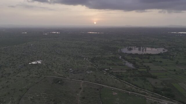 Aerial view of a pond near Padanga village in Ajmer, Rajasthan during monsoon, showing reflections of trees in water, lush green fields, and a forest in background with Ber, Ker, Babool, Rohida