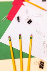 vertical flat lay of office supplies: pencils, paper clips, colorful folders, lined paper, and binder clips