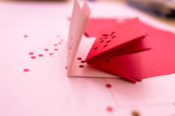 folded pink and red craft paper with holes punched out, Valentine's day crafting 