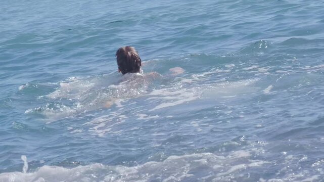 child swims joyfully in sea, enjoying summer vacation while learning essential water safety skills, Kid playing in sea waves