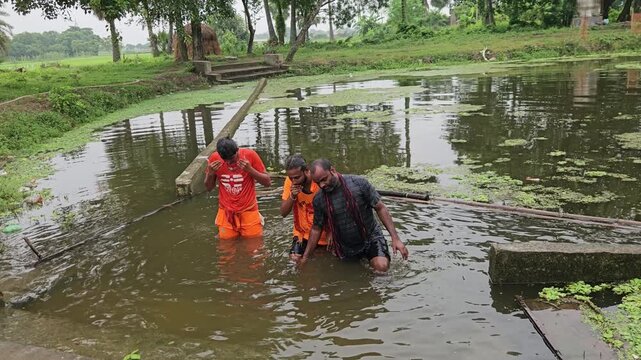 Footage of Kanwariya devotees taking a ritual bath in a village pond before collecting holy water (Gangajal) during sacred Kanwar Yatra pilgrimage in India. Ritual bathing is important purification