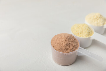 Protein powder. A spoonful of protein powder on a table. Different flavors of whey protein powder. Sports nutrition concept. Gym. Amino acid food supplement, creatine powder. Copy space.